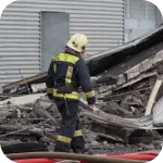 Post-Fire Structural Assessment by Experts – Engineers conducting a post-fire structural assessment, examining fire-damaged buildings to determine safety hazards, stability, and necessary repairs.